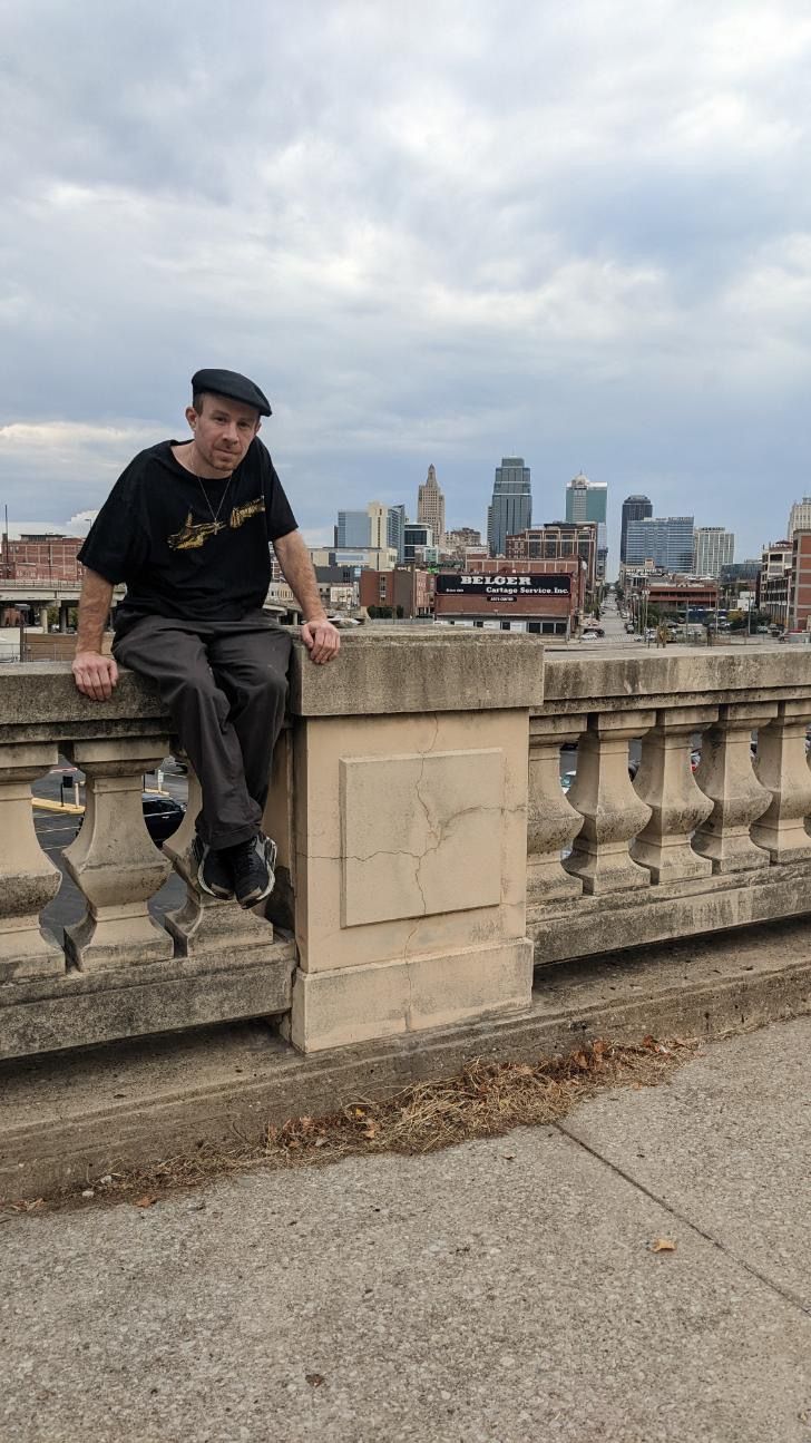 A woman is sitting at a desk with a laptop and a vase of flowers.