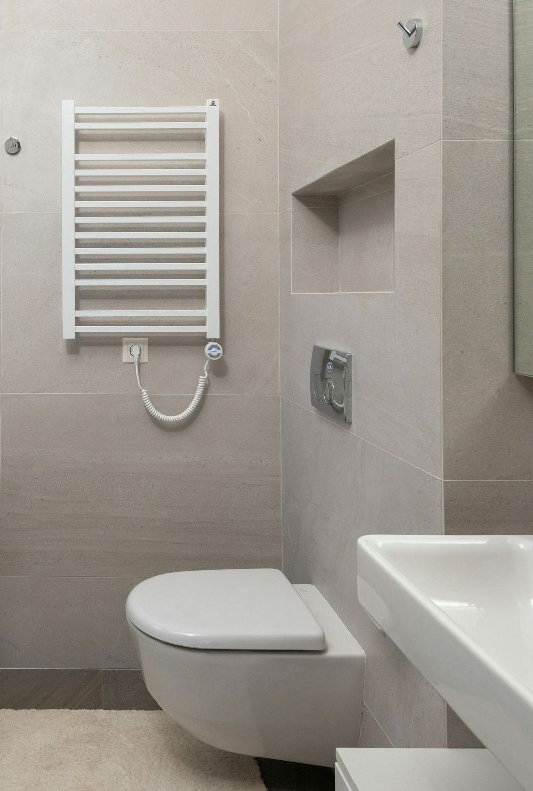 A bathroom with a toilet , sink , and towel rack.