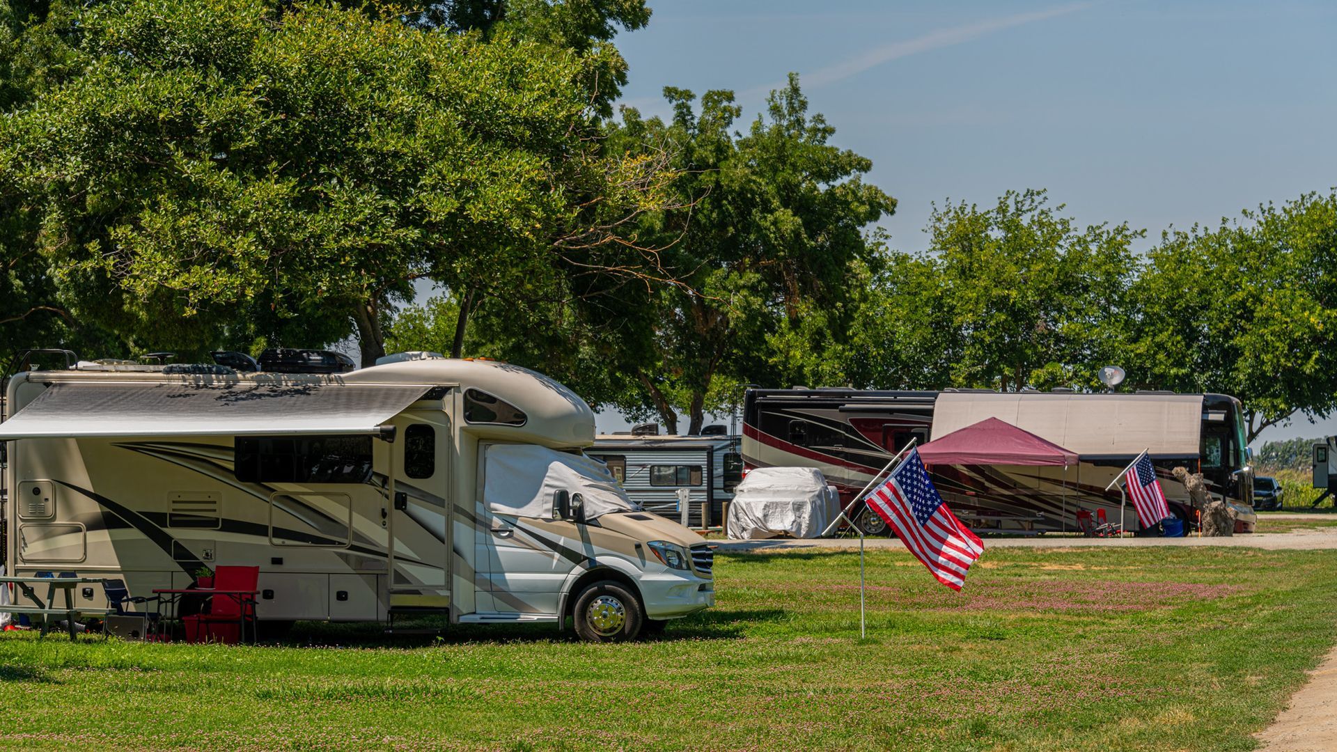 A rv is parked in a grassy field with an american flag.