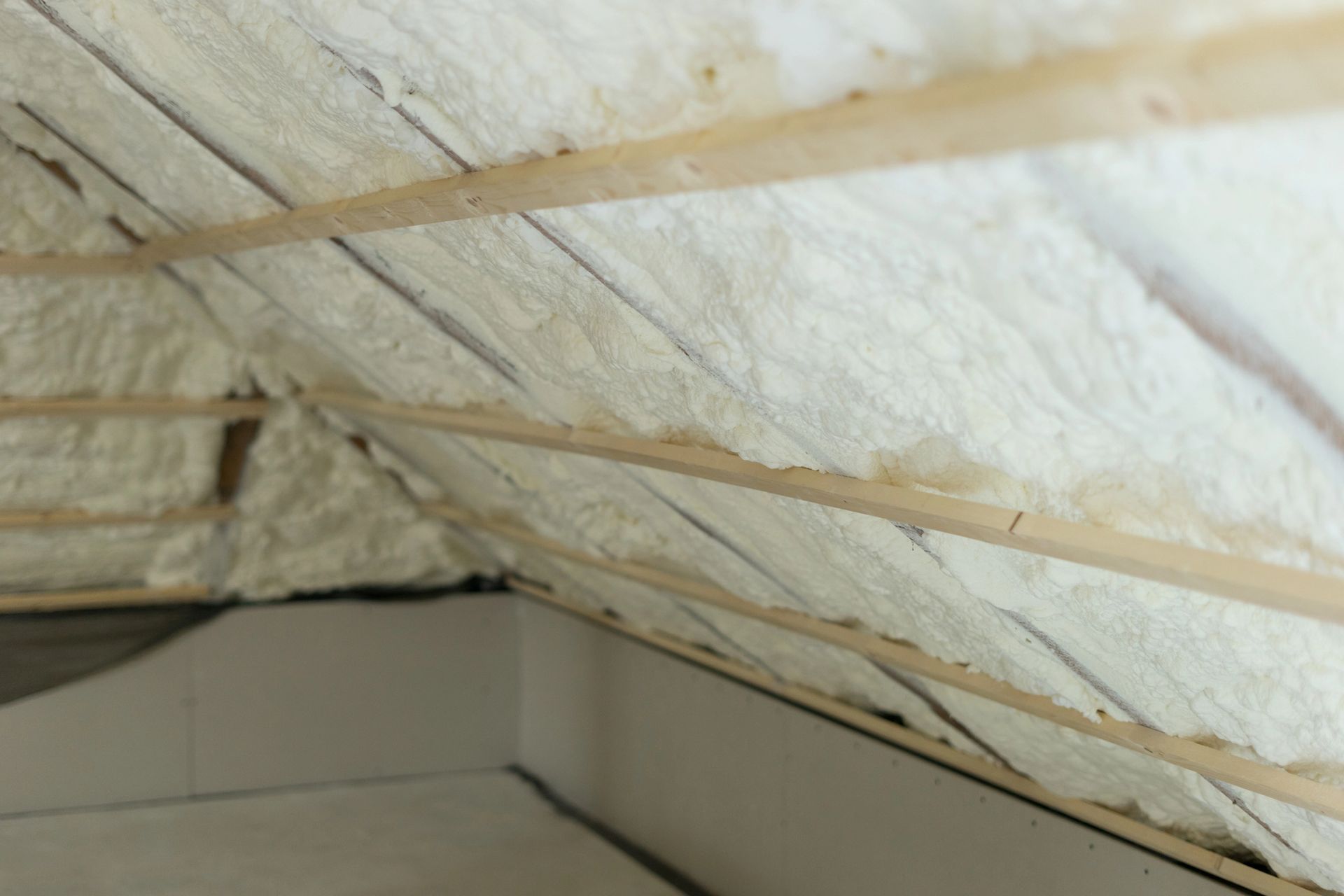 Expanding foam insulation creating an airtight barrier along the attic roofline.