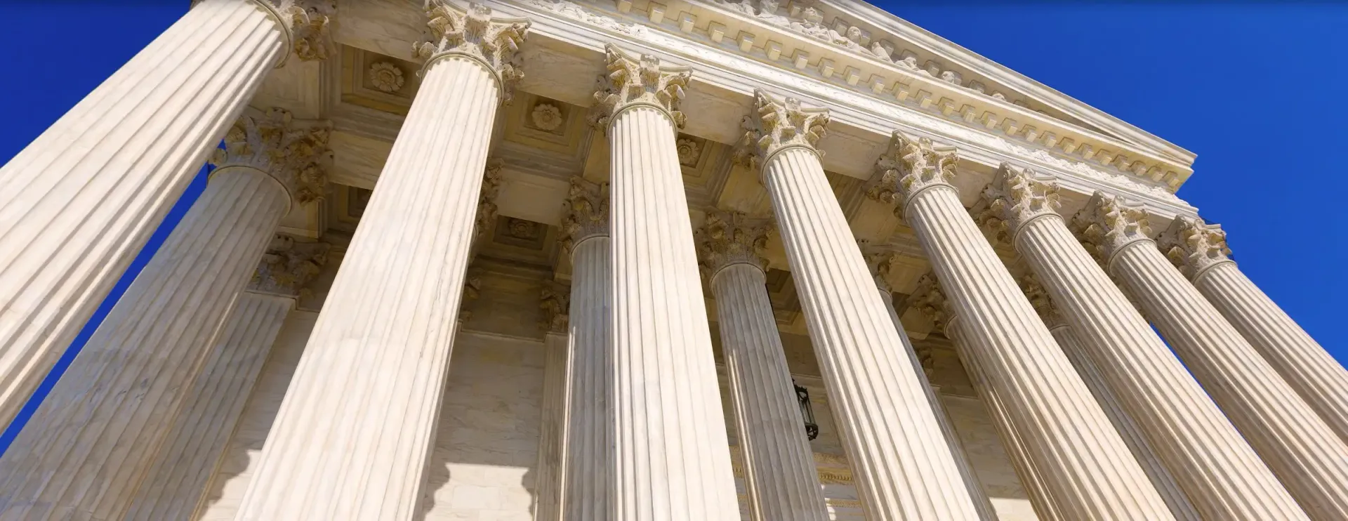 View of the US Supreme Court building, featuring columns against a blue sky.