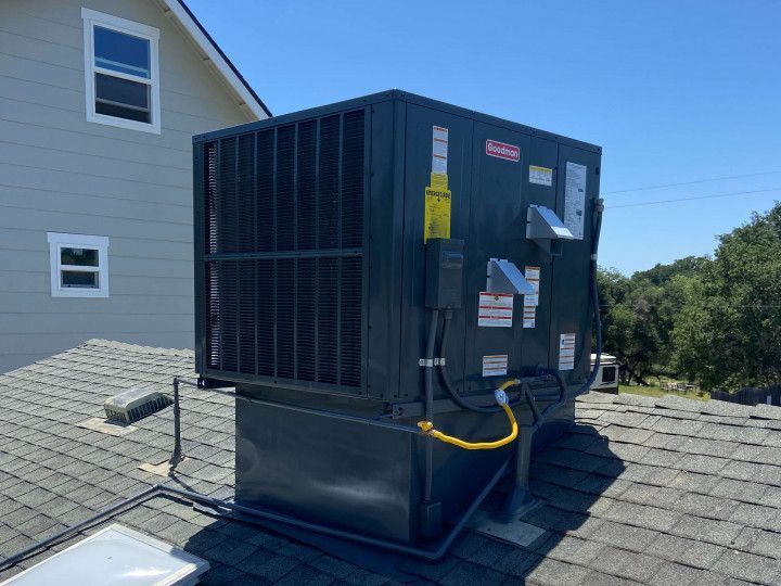 A black air conditioner is sitting on the roof of a house.