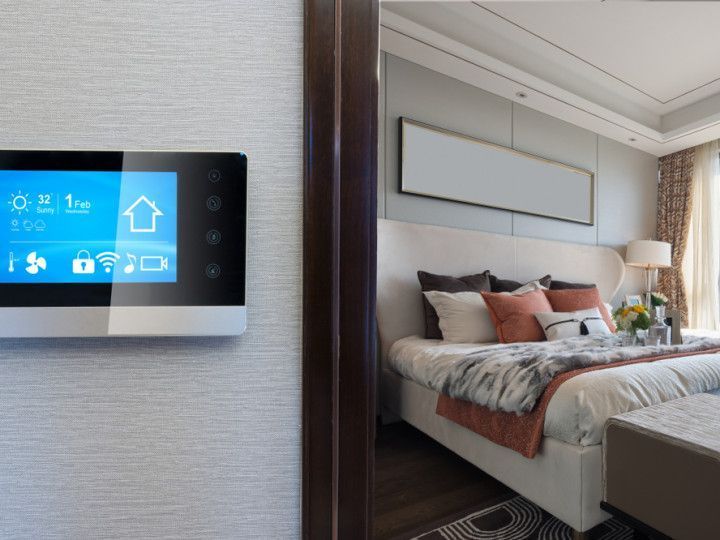 A bedroom with a bed and a thermostat on the wall.
