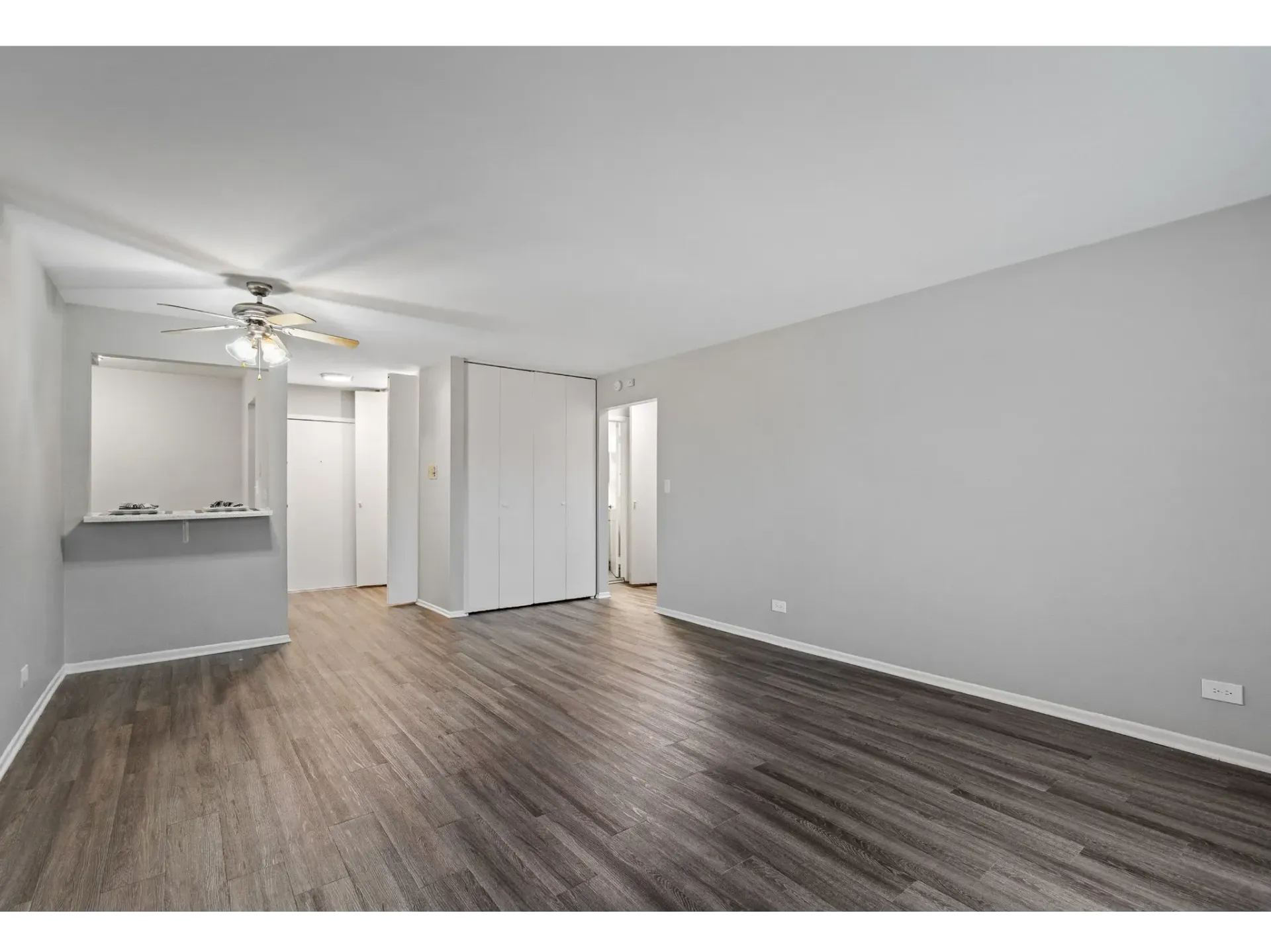 Interior view of an apartment unit featuring hardwood flooring and a ceiling fan.