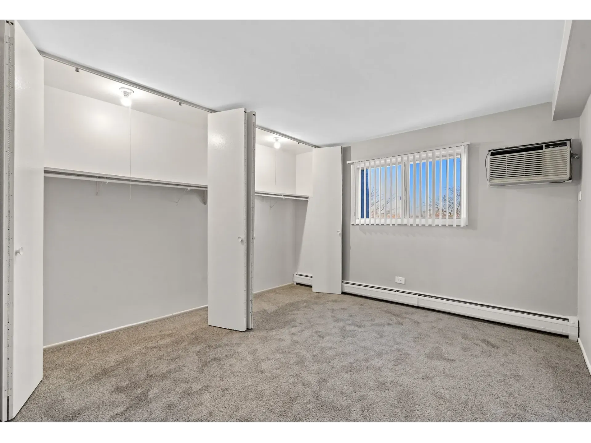 A spacious, empty bedroom with carpeted floors and built-in closets.