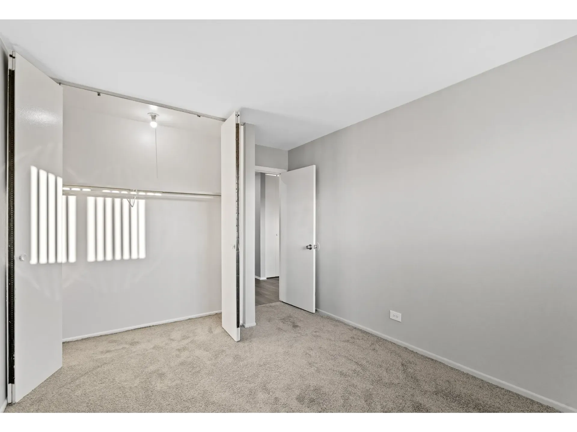Interior view of a carpeted bedroom with closet and light fixture