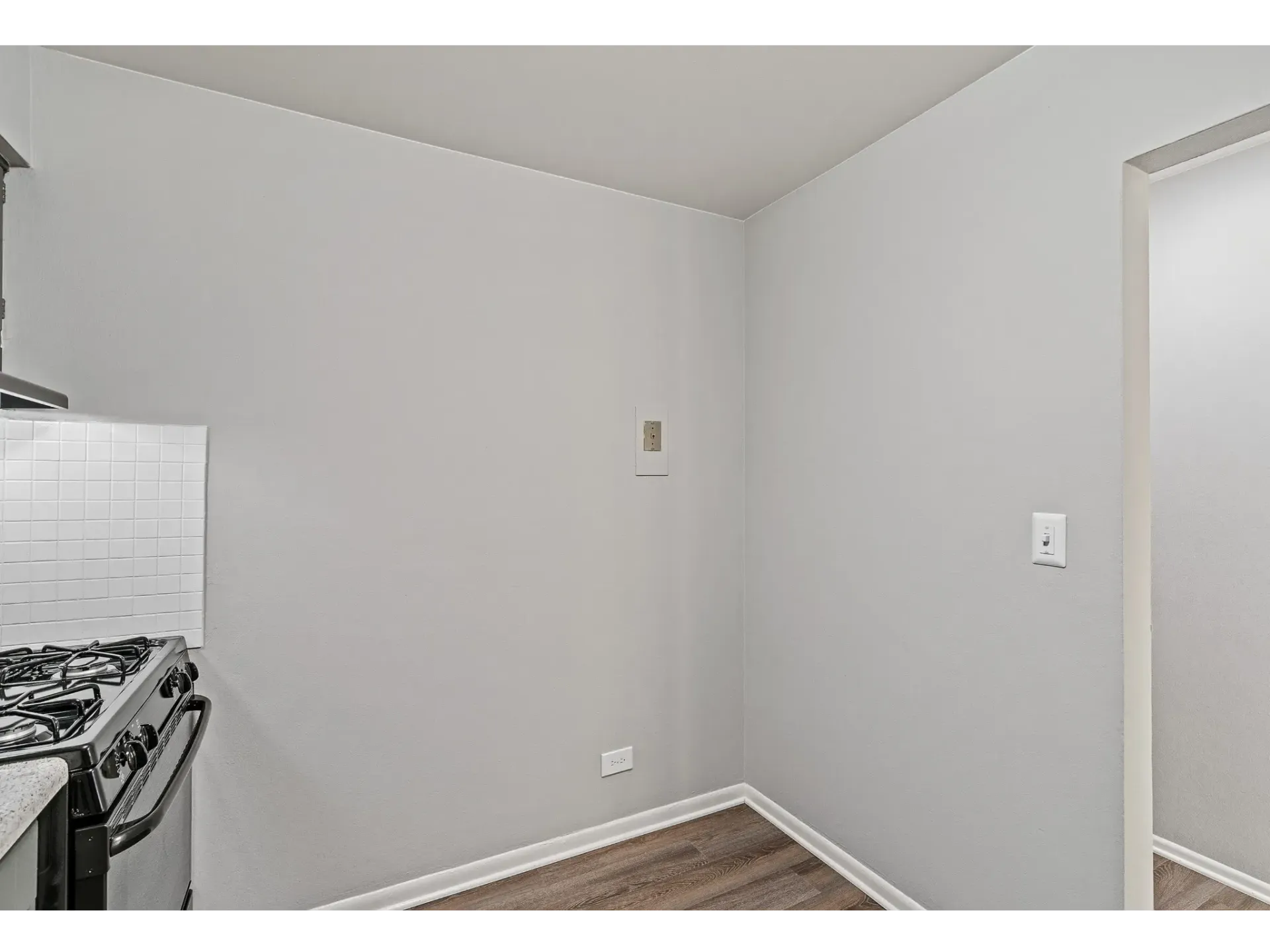 Interior view of a small kitchen space with a gas stove and light-colored walls.