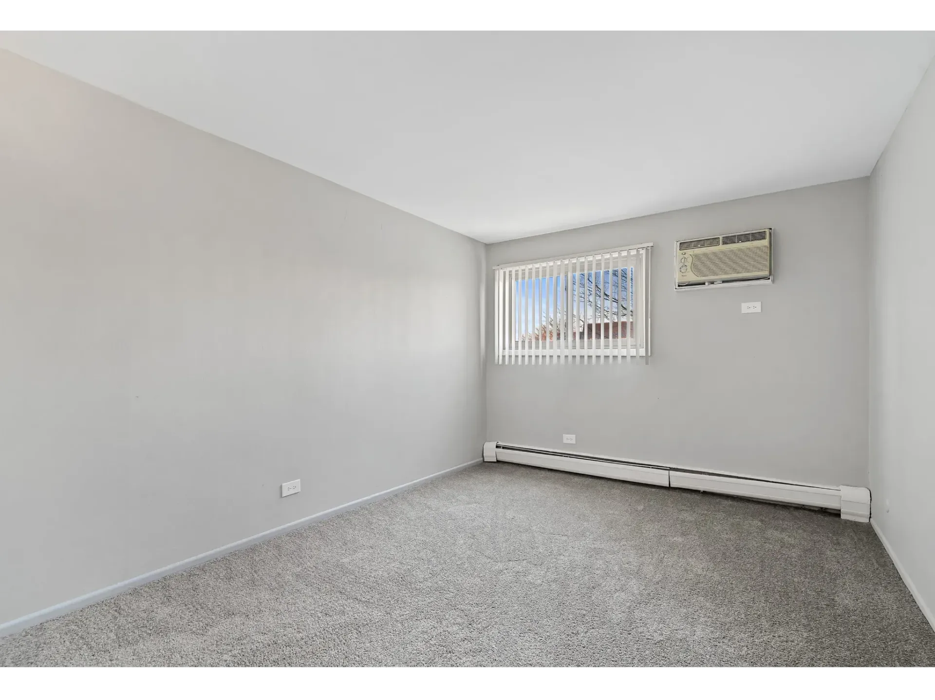 Empty apartment room with carpet and air conditioning unit
