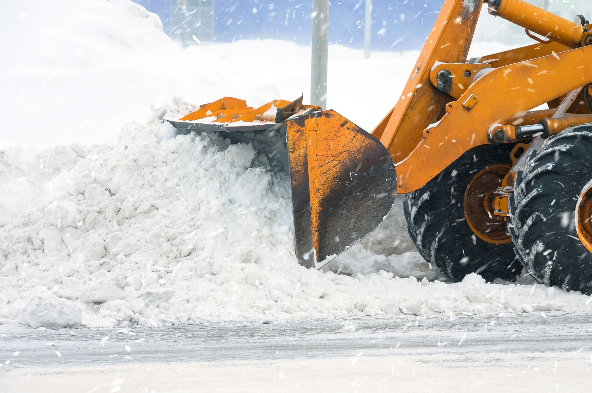 A yellow snow plow is clearing snow from a road.