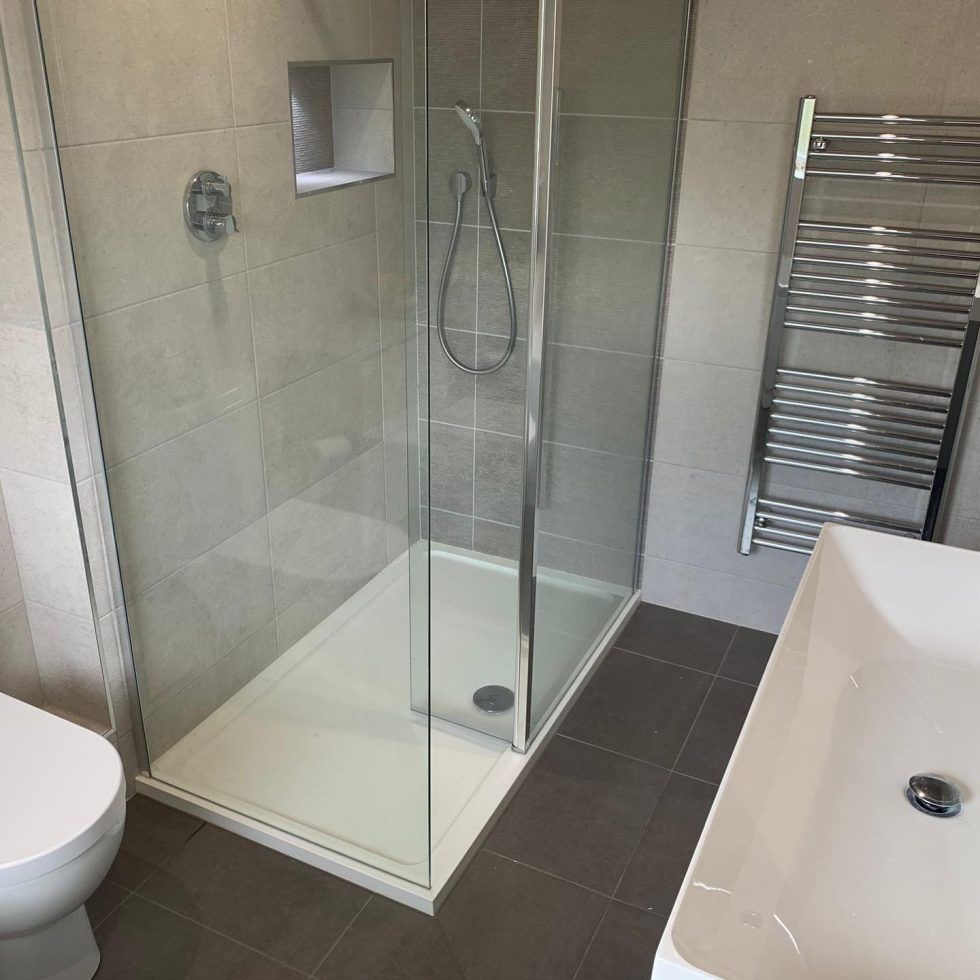 Modern bathroom featuring a glass-enclosed shower, a wall-mounted towel radiator, and a white sink basin.