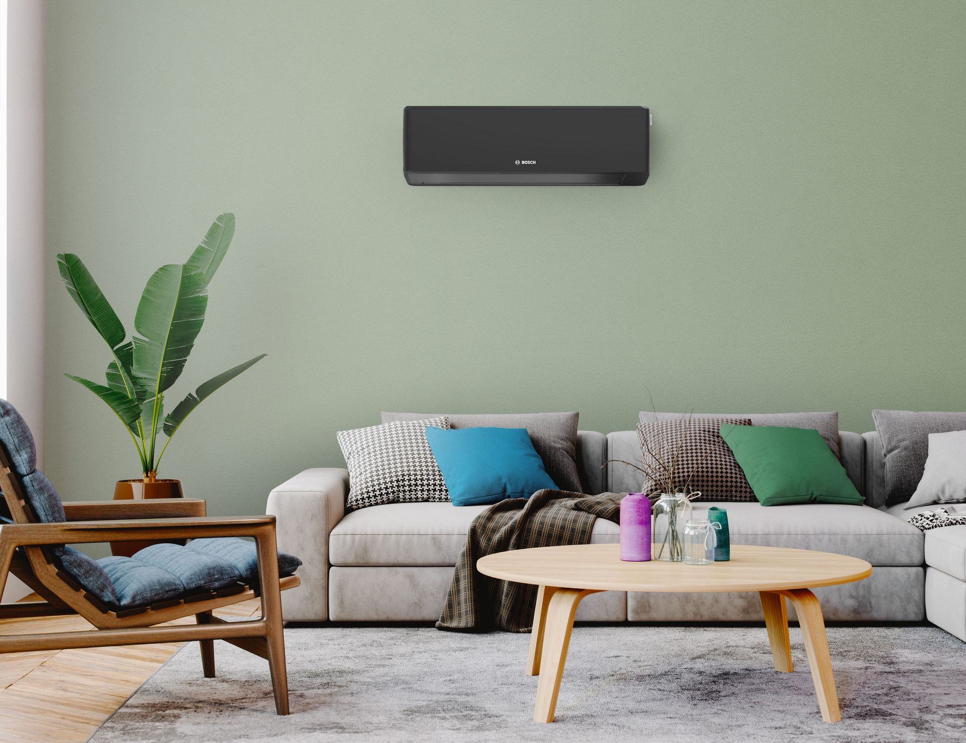 A dark wall-mounted air conditioner unit in a modern living room with a gray sofa, wooden coffee table, and a houseplant.
