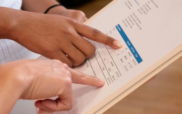 Two individuals point to data on a printed document, discussing information in a professional setting.