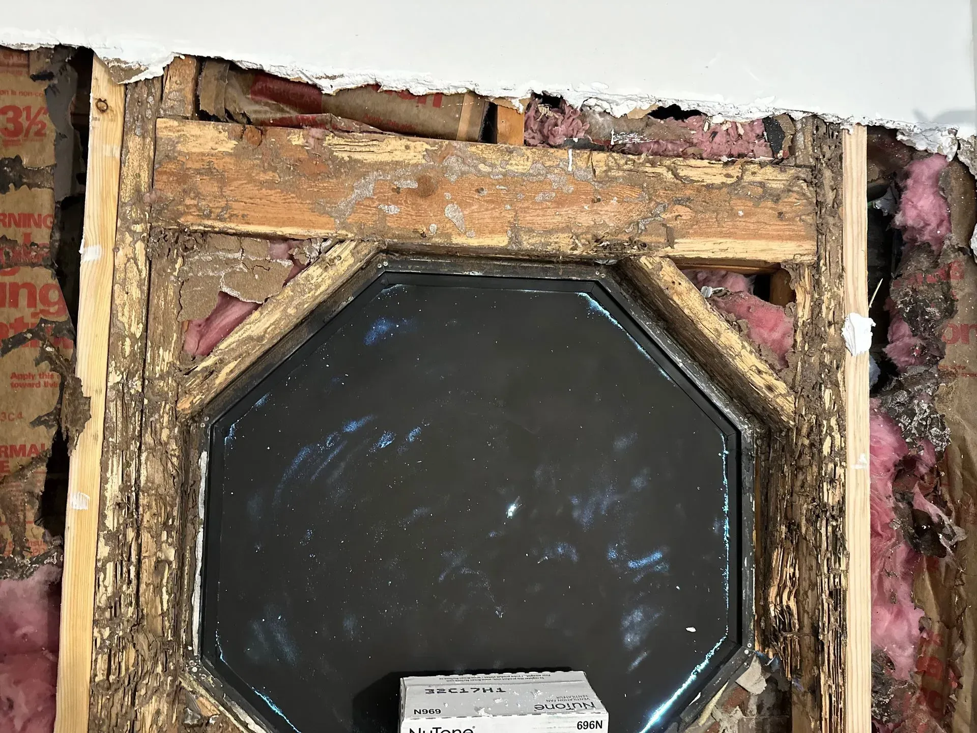 Window frame with octagon-shaped opening, surrounded by exposed wall framing and insulation.