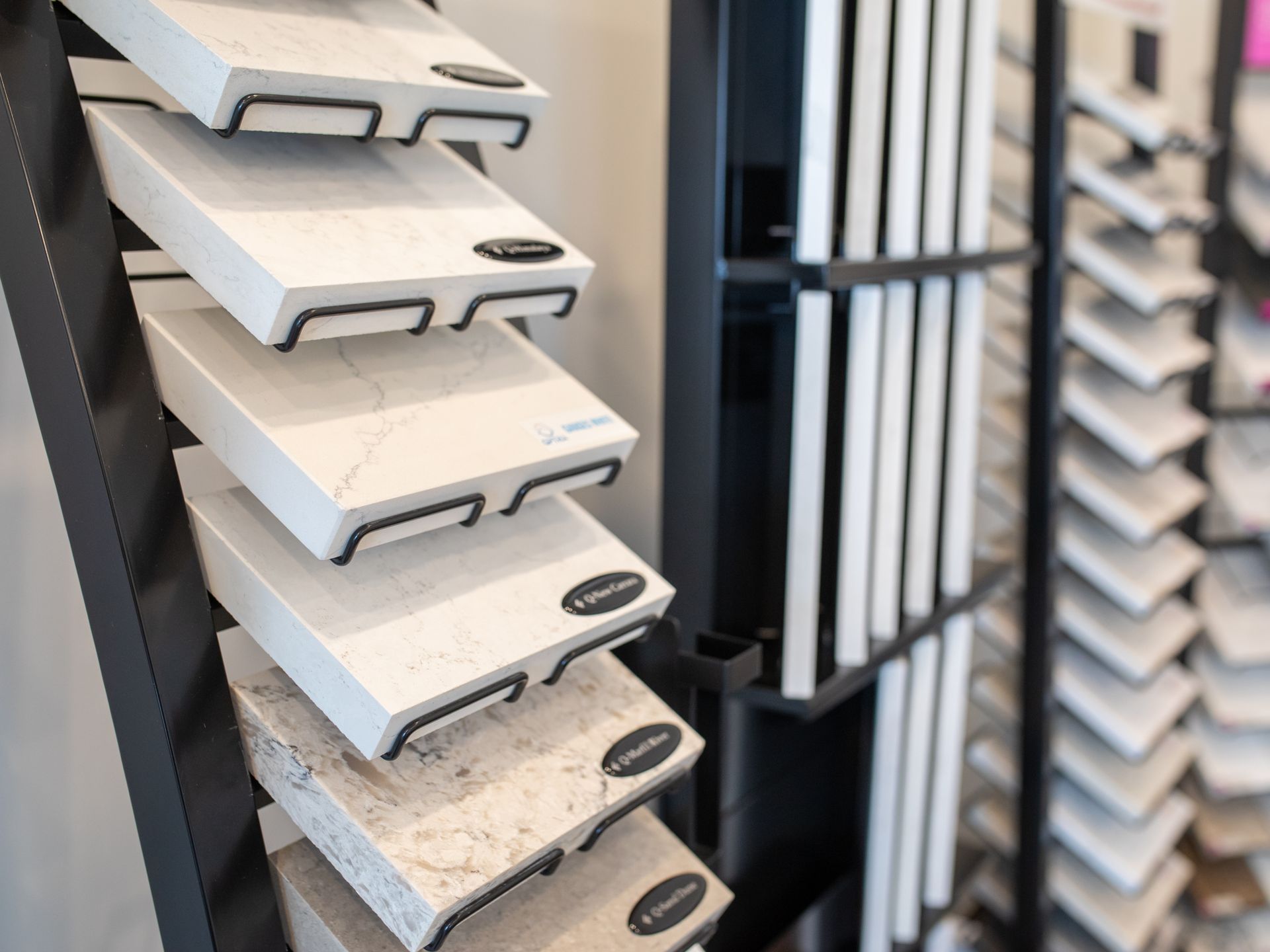 Display of countertop samples in a store; white, light brown, and speckled stone.
