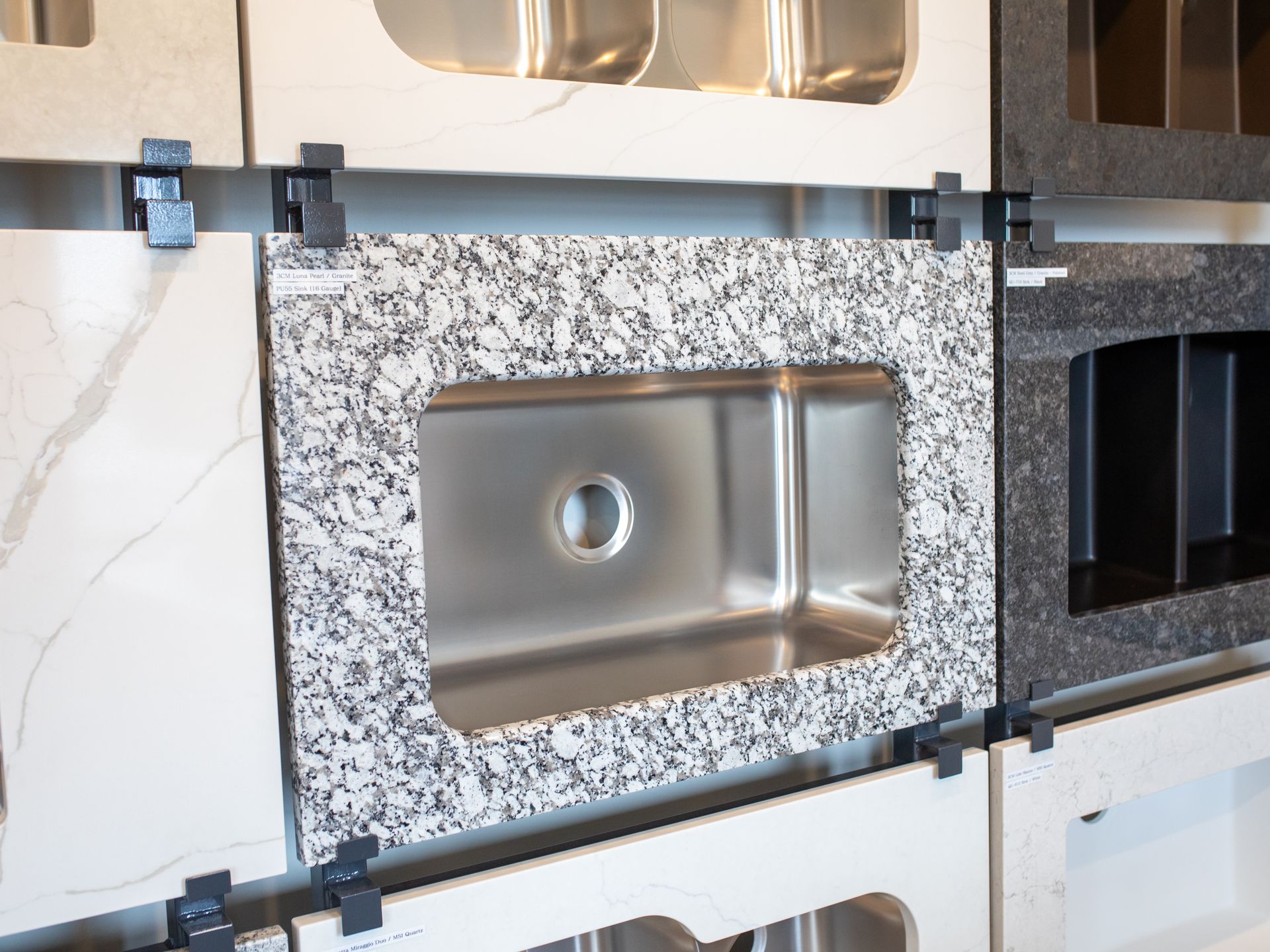 Kitchen sink countertop display with granite surround and stainless steel basin.