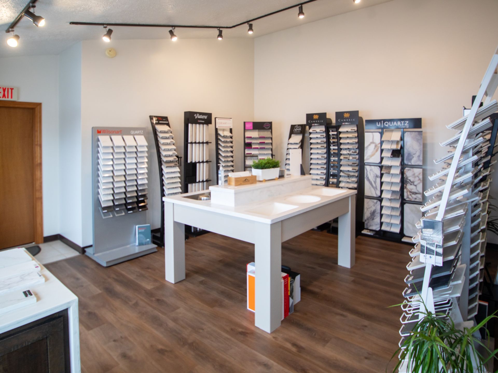 A showroom with countertop samples and displays, wooden floor, overhead lighting.