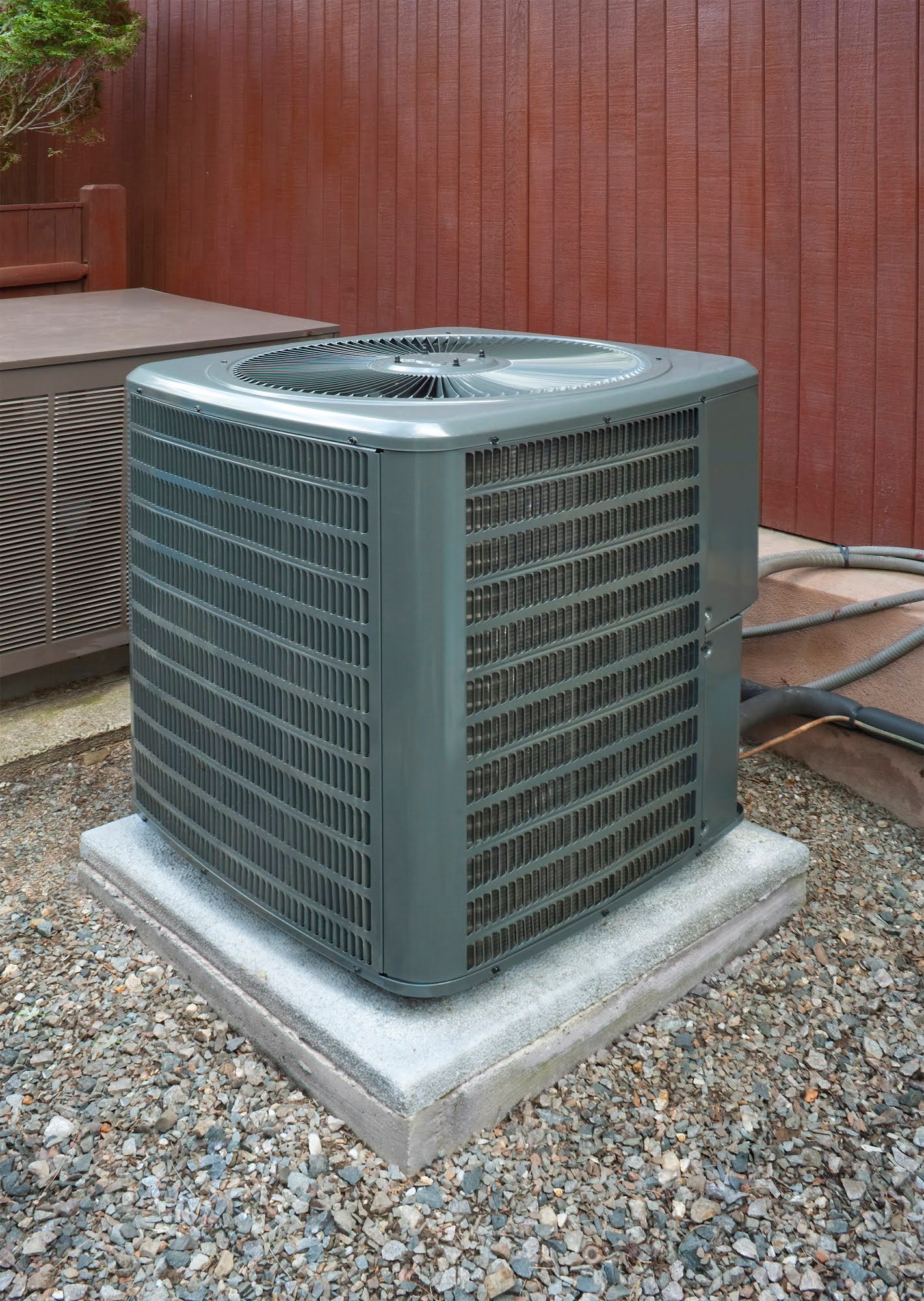 A large air conditioner is sitting on top of a pile of gravel.