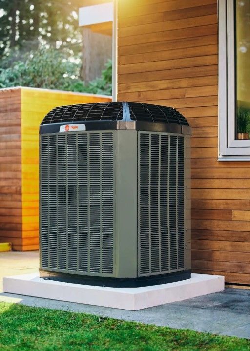 A large air conditioner is sitting on the side of a house.