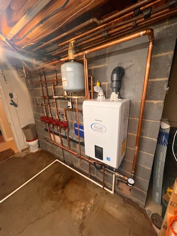 A boiler is installed in a basement next to a brick wall.