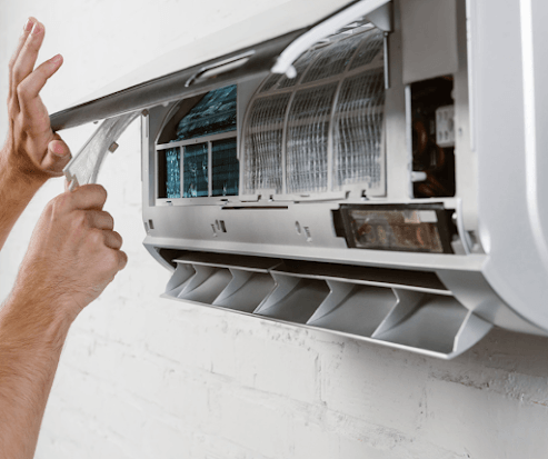 A person is cleaning the filter of an air conditioner.