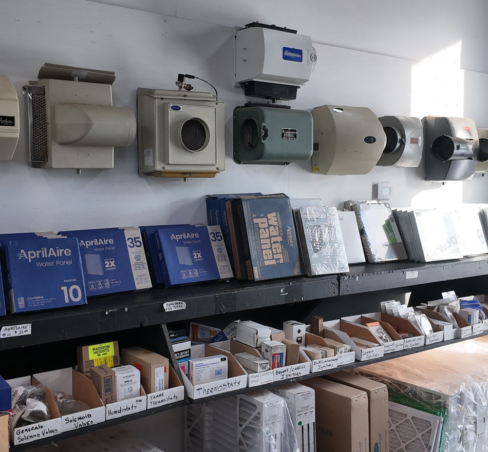 Humidifiers and filters on shelves in a store, with boxes and parts below.