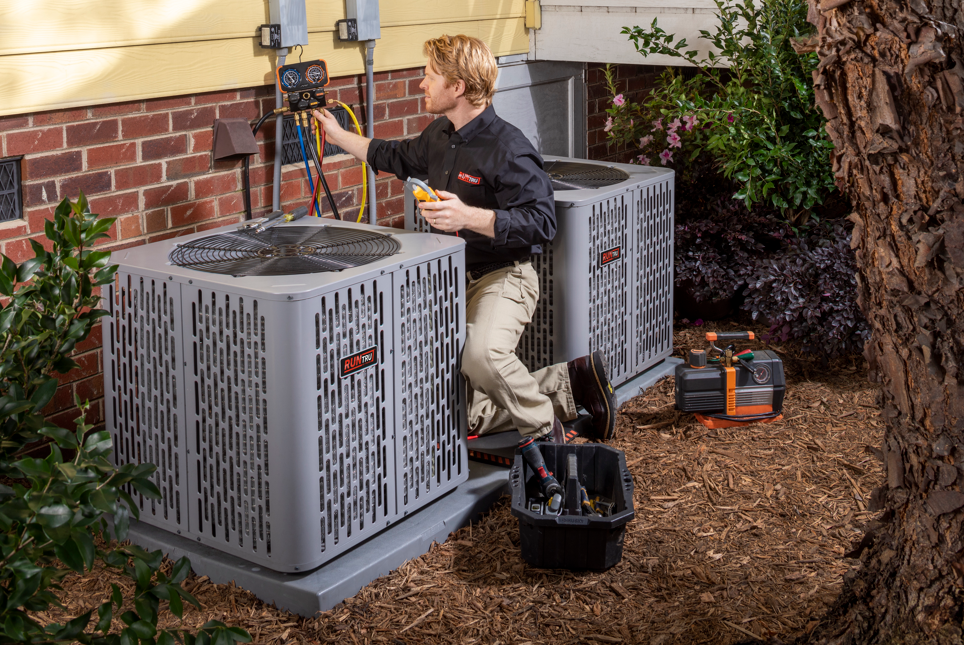 A technician with a screwdriver is repairing an air conditioner. A technician with a screwdriver is repairing an air conditioner.