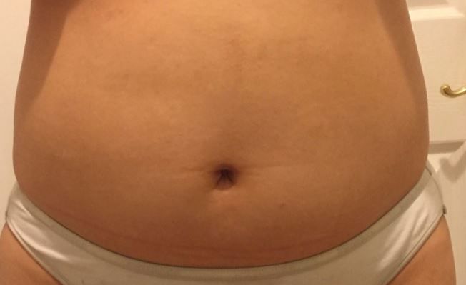 A woman 's belly is shown in white underwear.