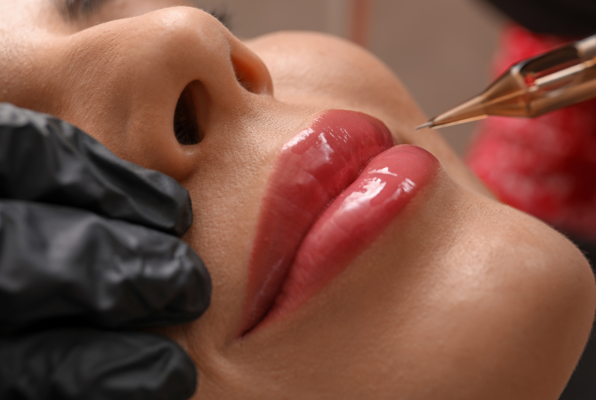 A woman is getting a permanent lip tattoo on her lips.