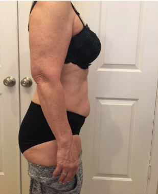 A woman in a black bra and black underwear is standing in front of a white door.