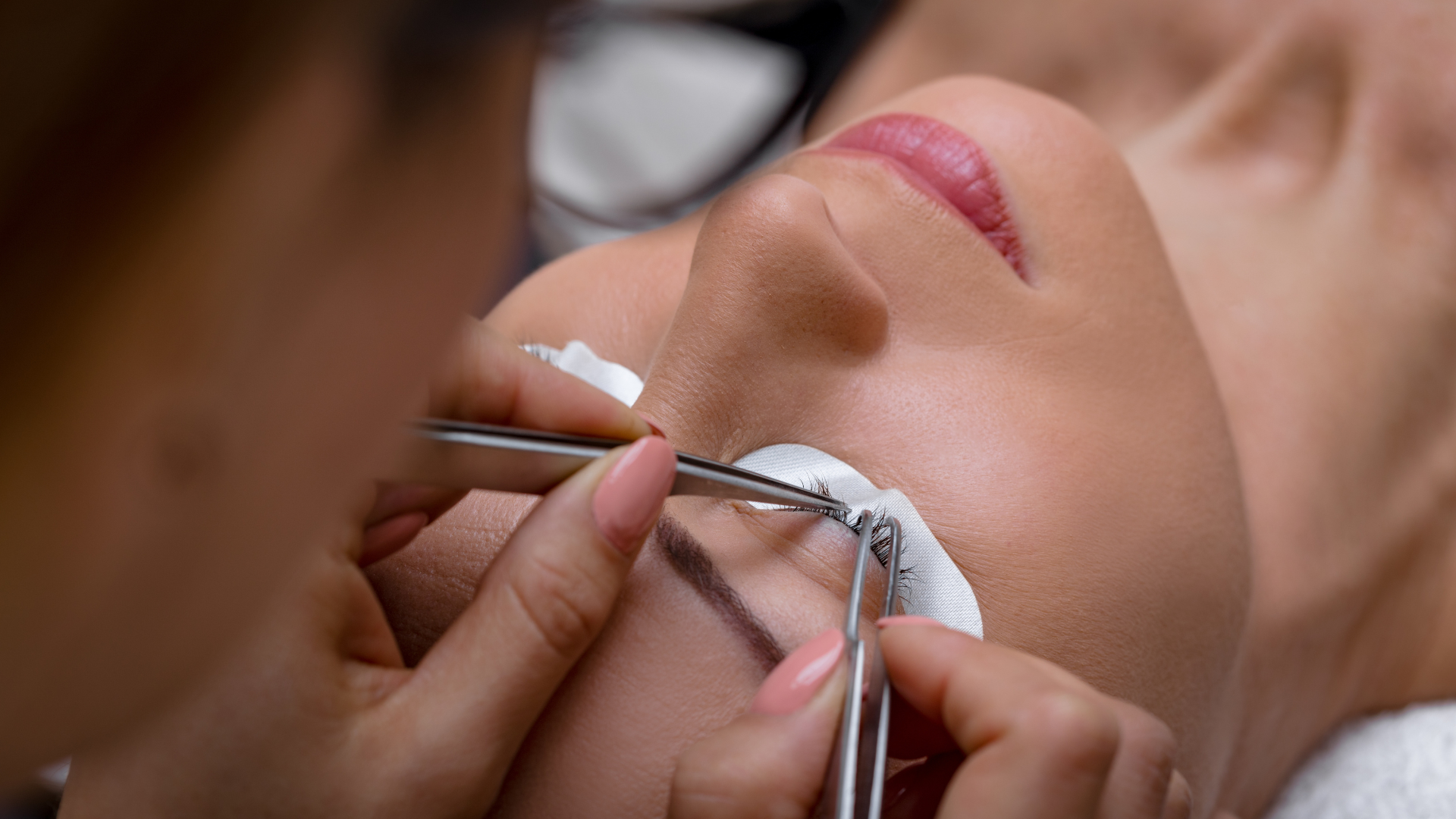 A woman is getting eyelash extensions in a beauty salon.
