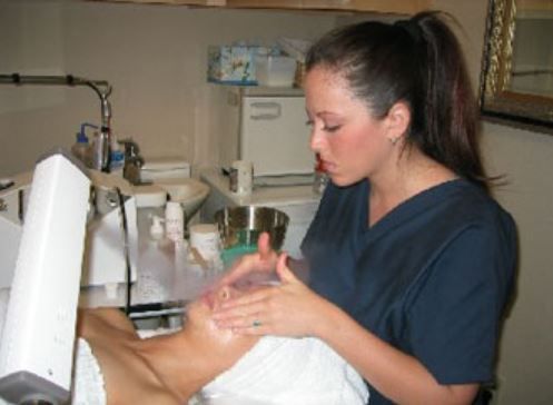 A woman in scrubs is giving a man a facial