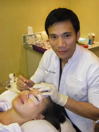 A man in a lab coat is working on a woman 's eyelashes