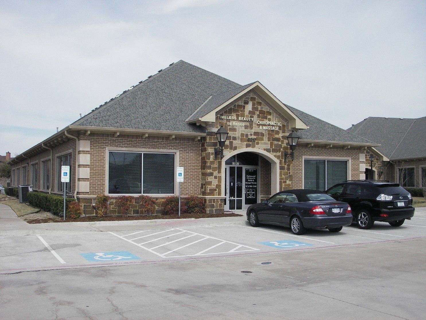 Two cars are parked in front of a large building