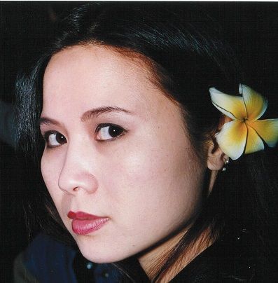 A woman with a flower in her hair looks at the camera