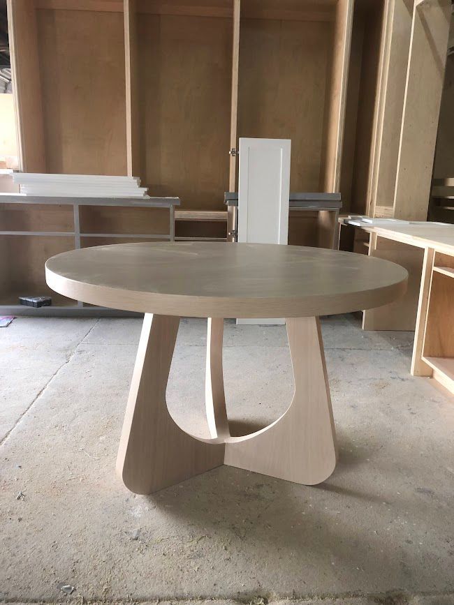 A wooden table is sitting in a room surrounded by wooden cabinets.