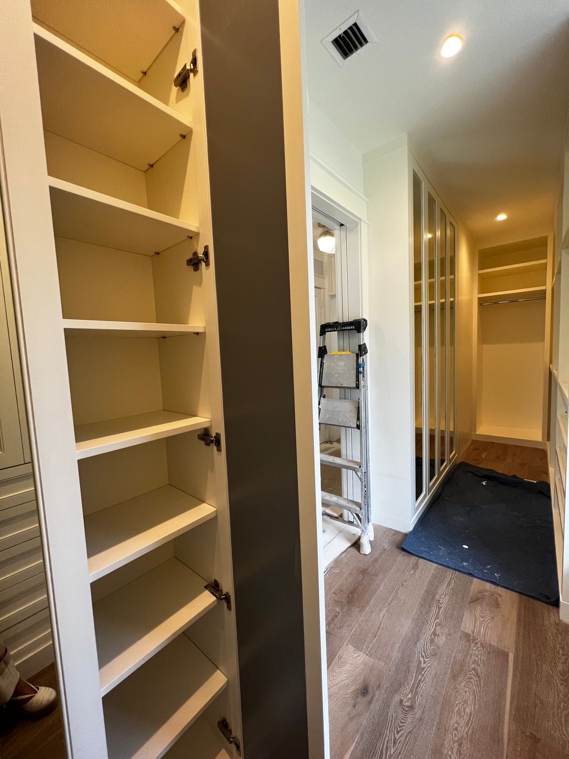 A walk in closet with lots of shelves and a mirror.