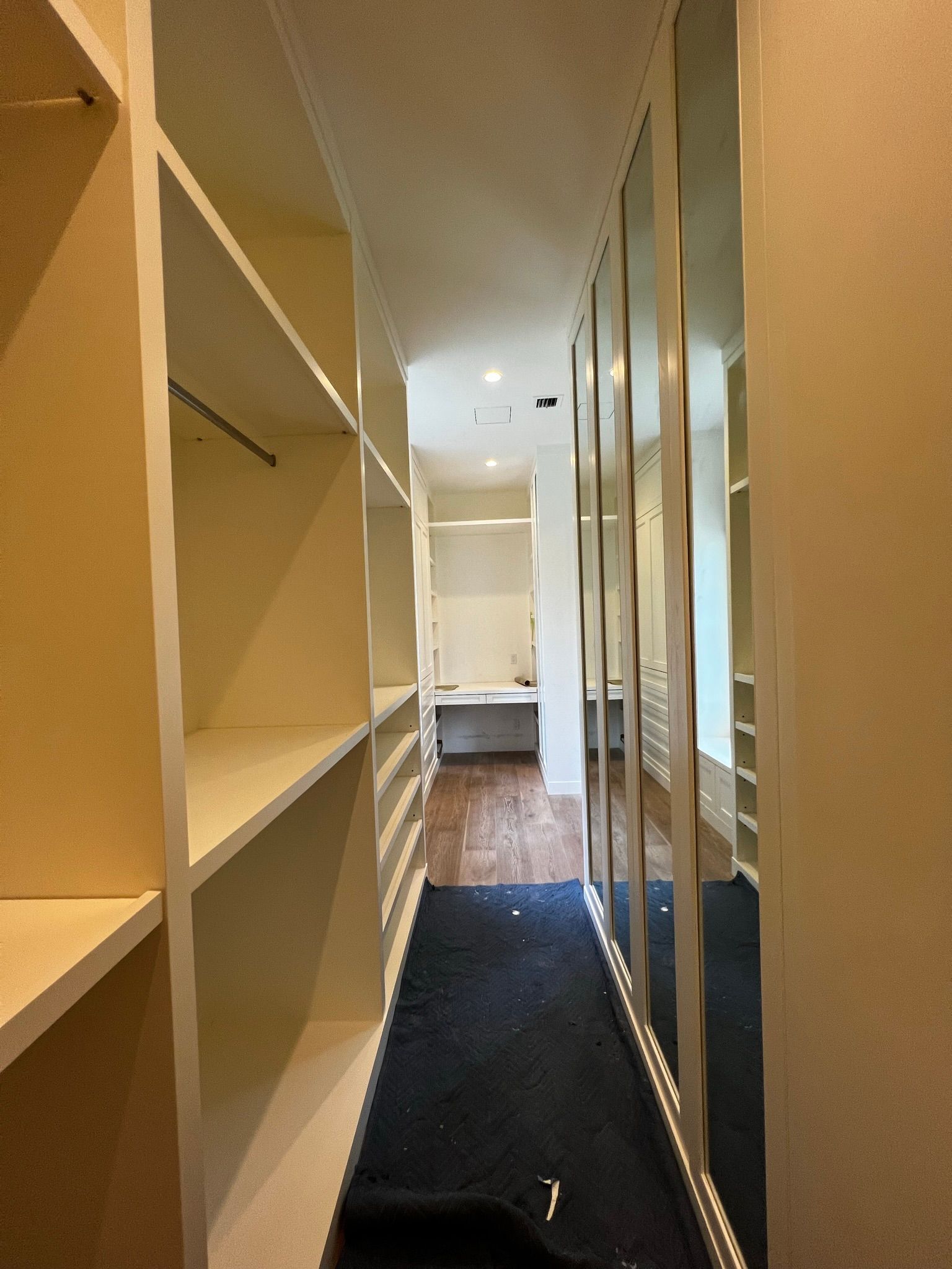 A walk in closet with lots of shelves and mirrors