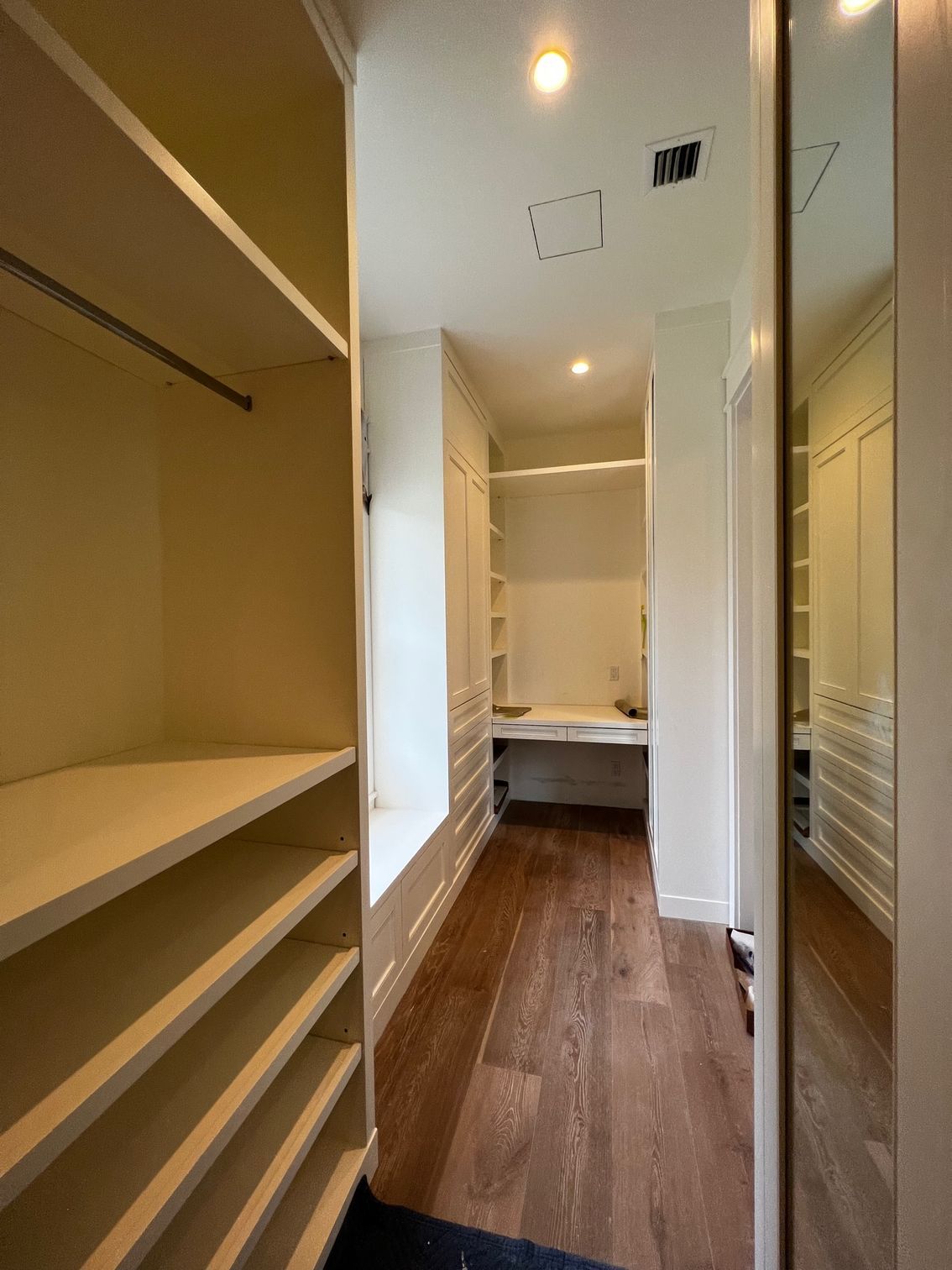 A walk in closet with lots of shelves and a desk.