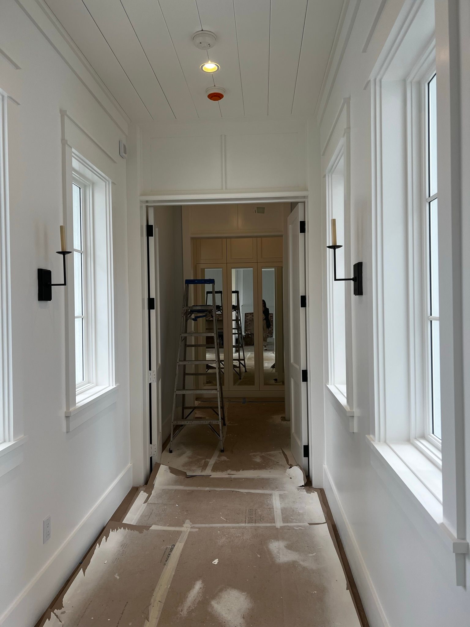 A long hallway with a ladder and lots of windows