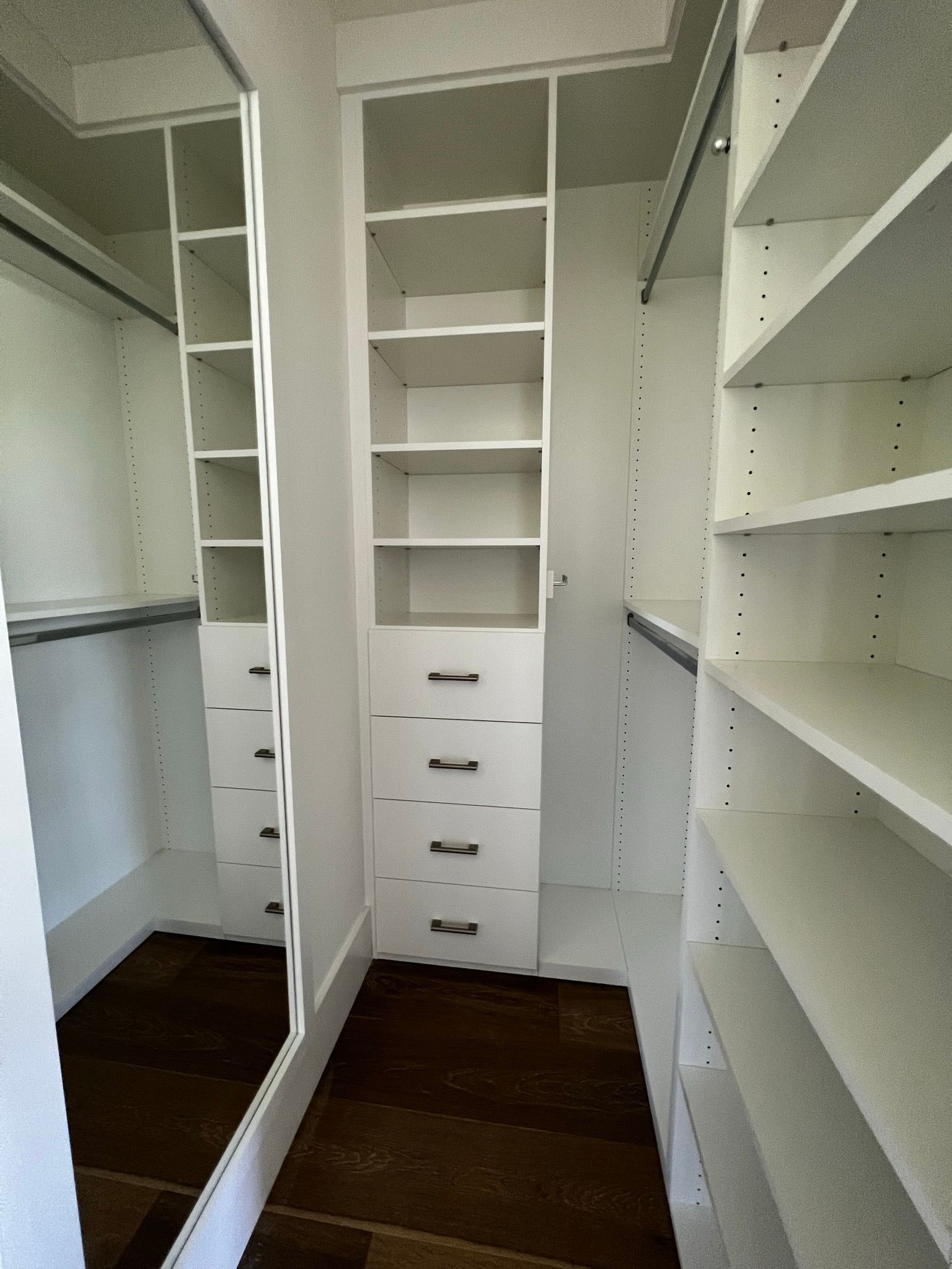 A walk in closet with lots of shelves and drawers