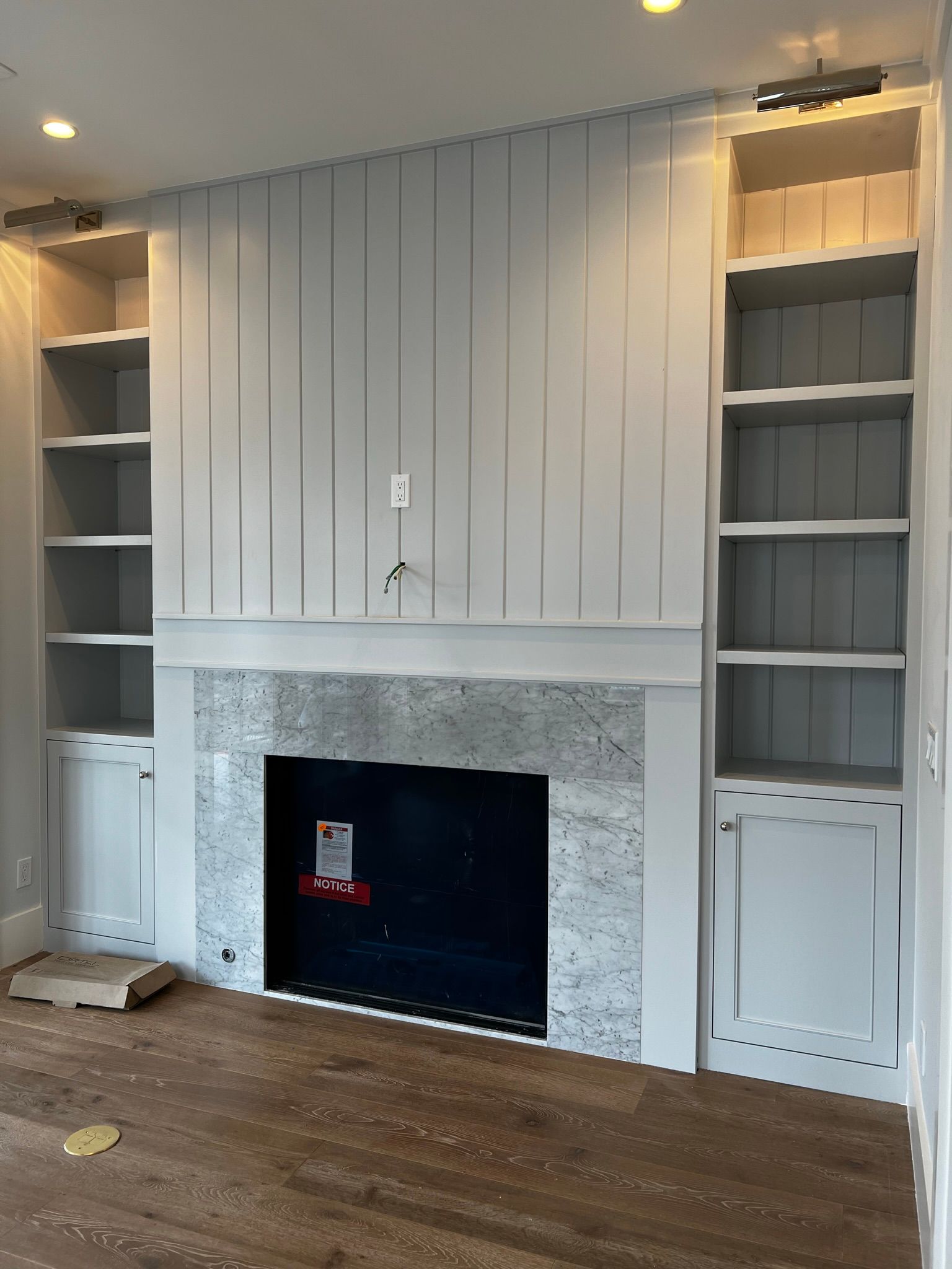 An empty living room with a fireplace and shelves