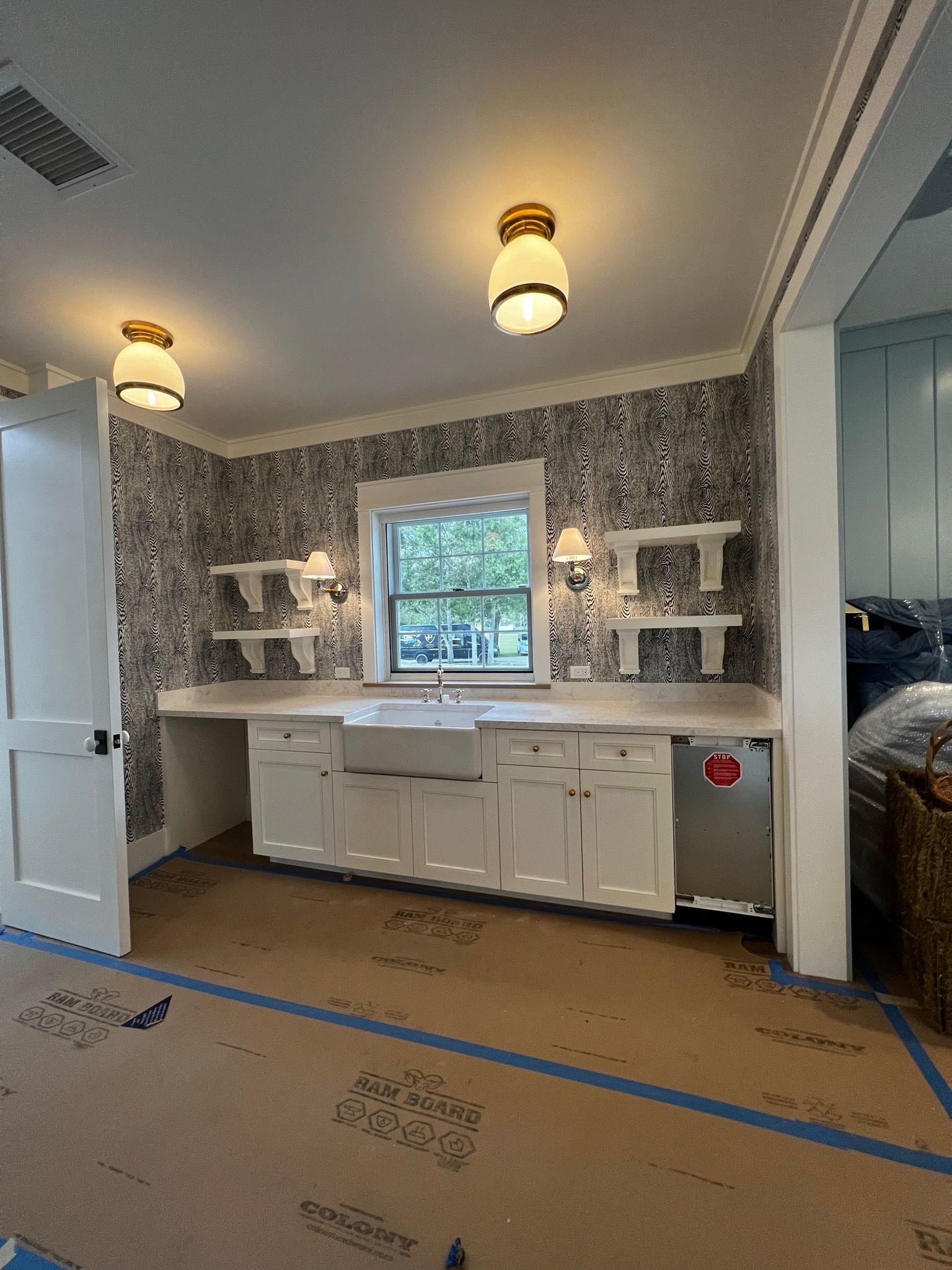 A kitchen with white cabinets , a sink , and a window.