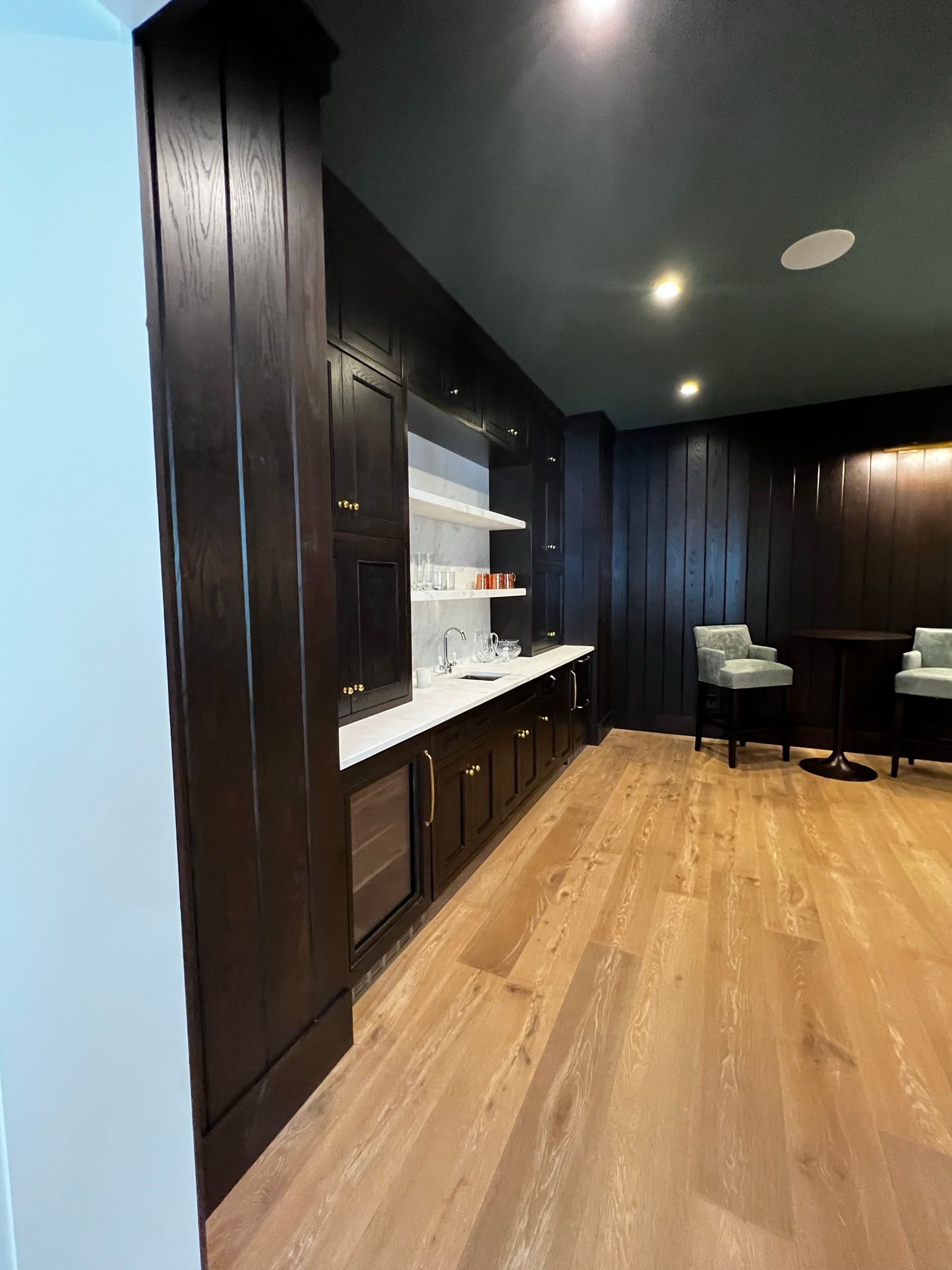 A room with hardwood floors , black cabinets , a table and chairs.