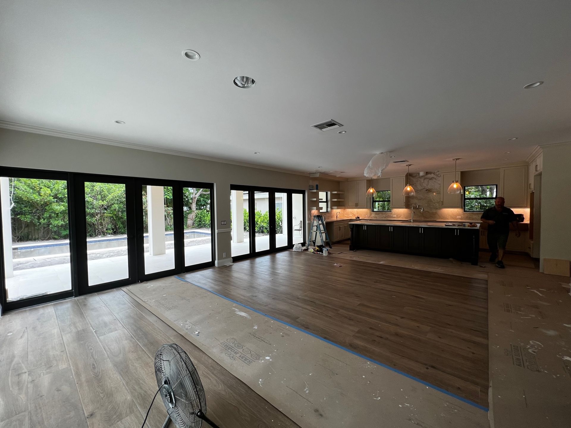 A large empty room with a lot of windows and a kitchen in the background.