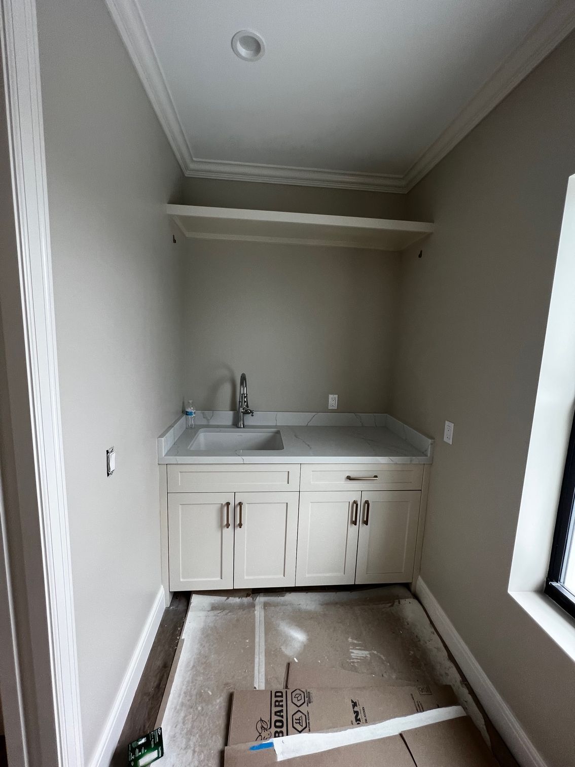 An empty room with a sink and a shelf