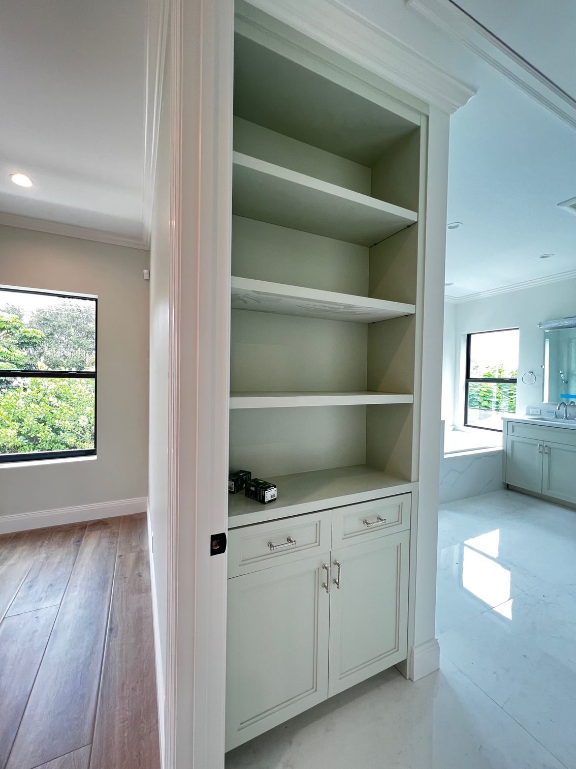 A corner of a room with white cabinets and shelves