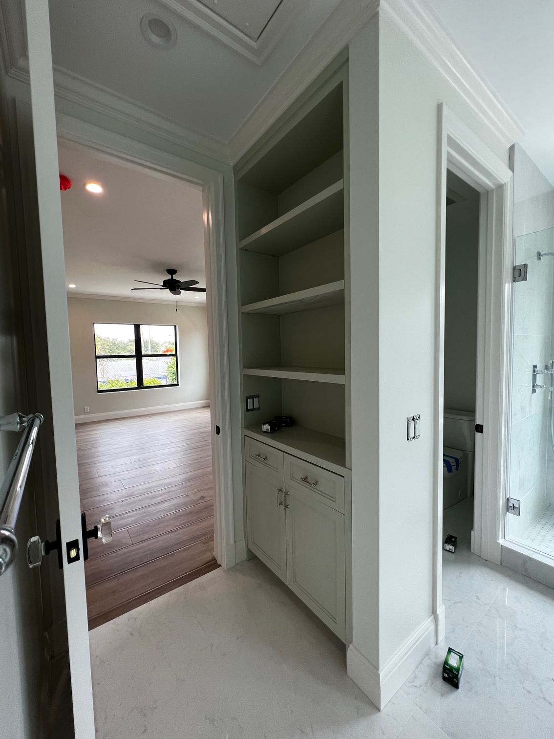 A bathroom with a walk in shower and a closet with shelves.