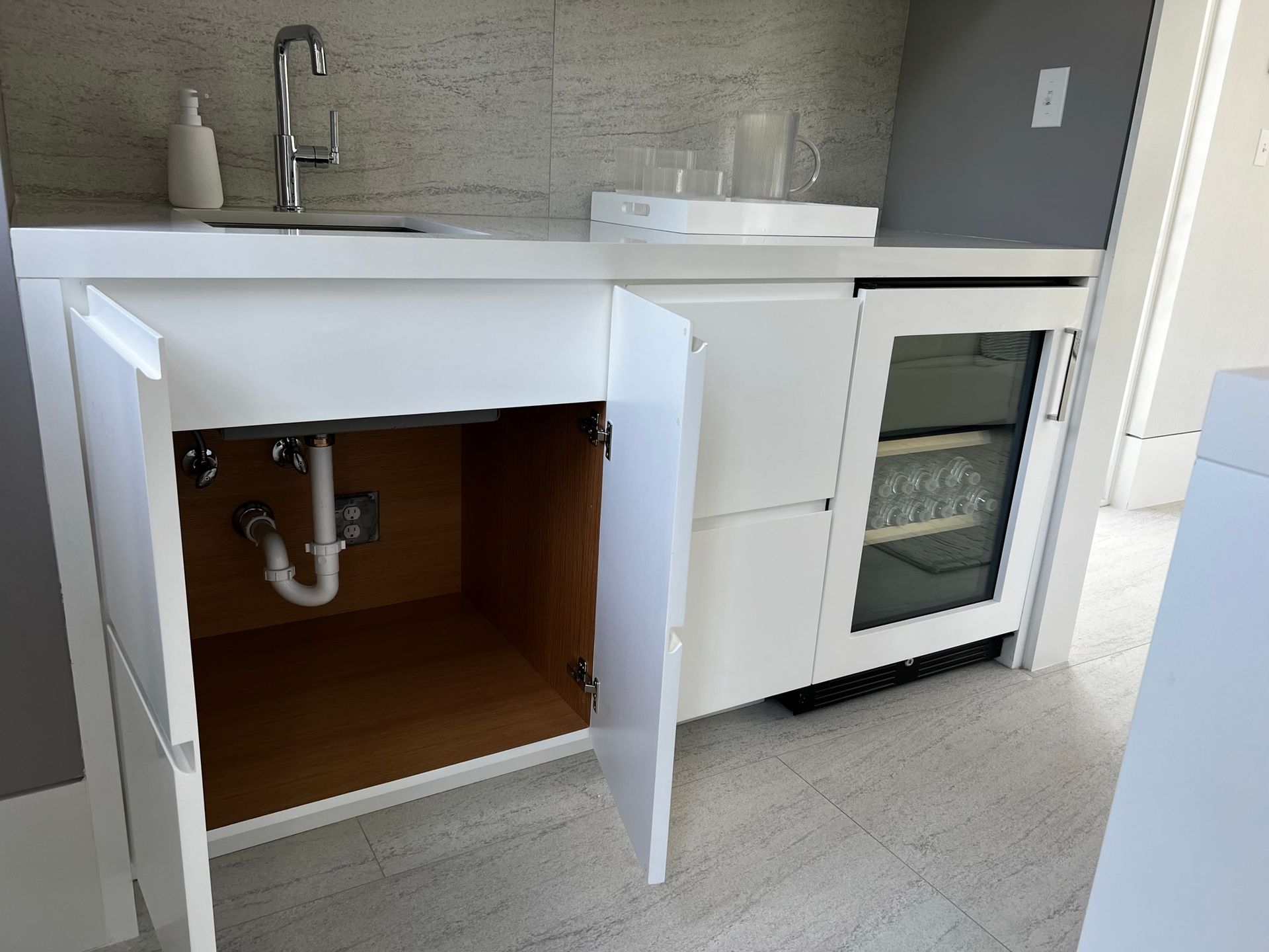 A kitchen with a sink and a refrigerator underneath it.