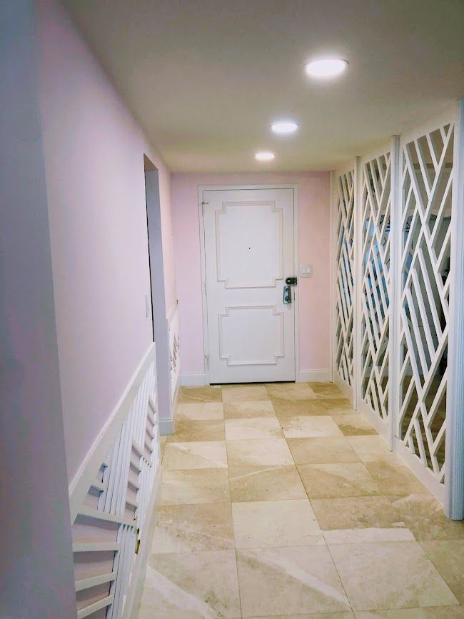 A hallway with a white door and a tiled floor.