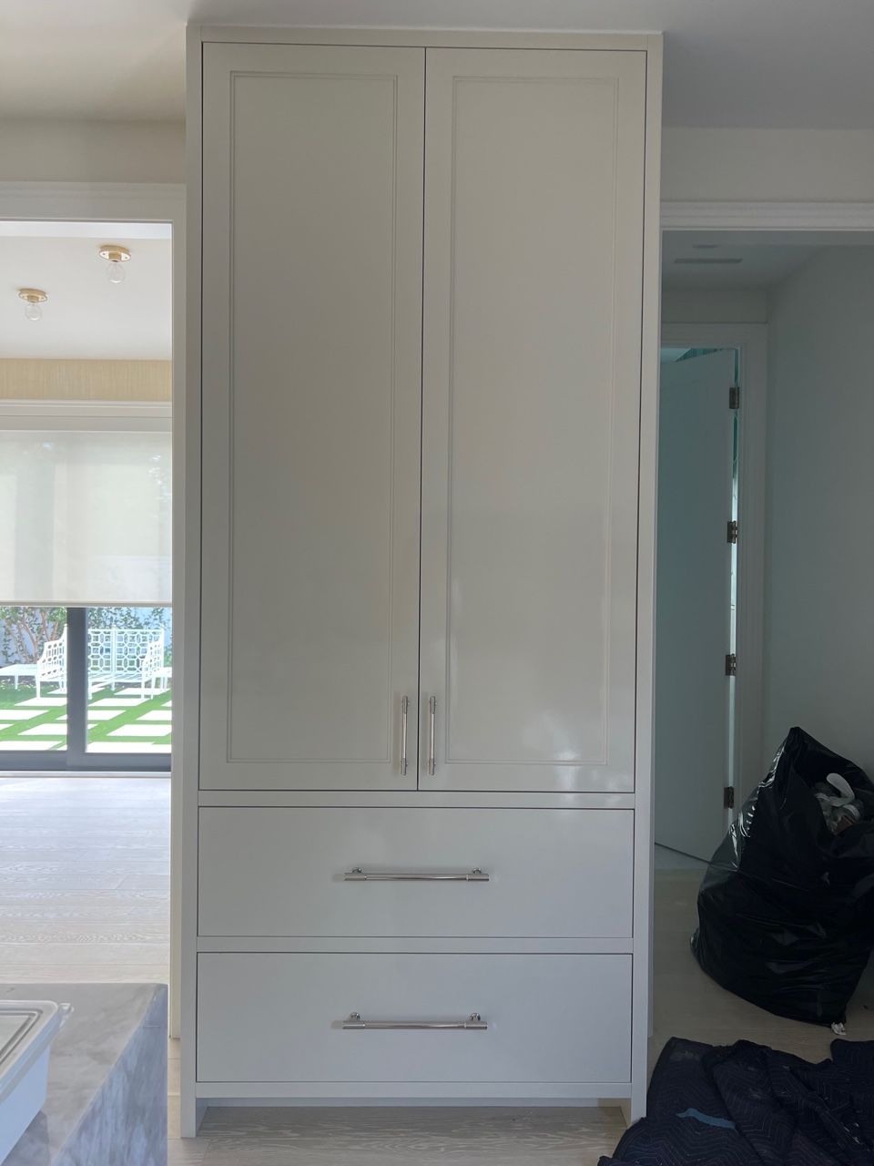 A white cabinet with drawers in a room next to a window.